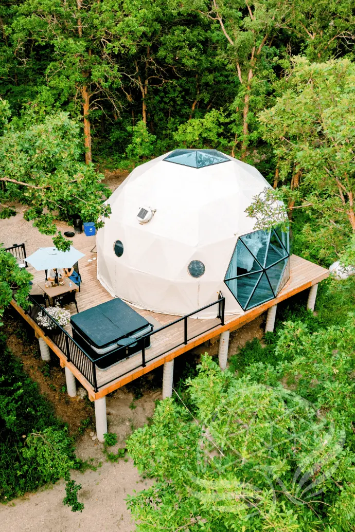 a geodesic dome with private deck, table and hot tub