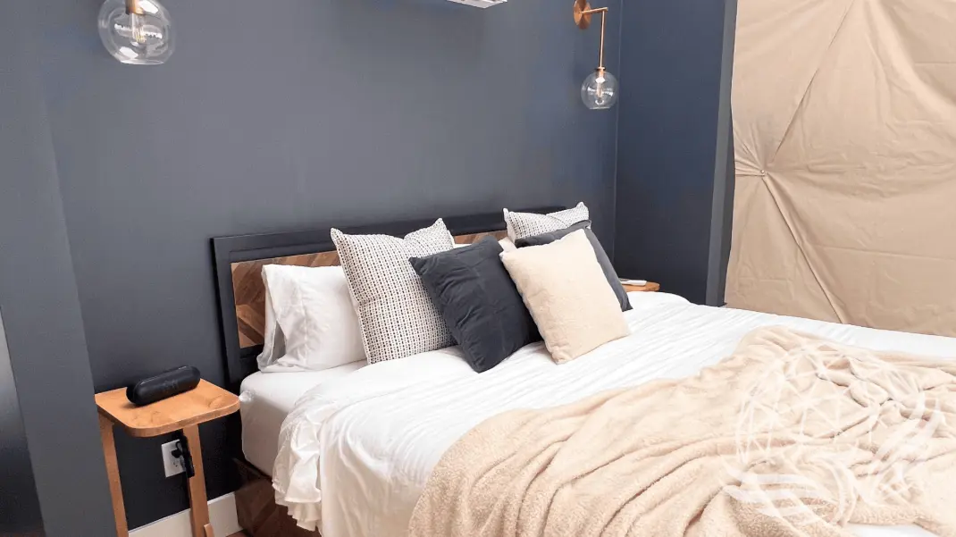 a cozy bed with pillows and blanket inside a geodesic dome