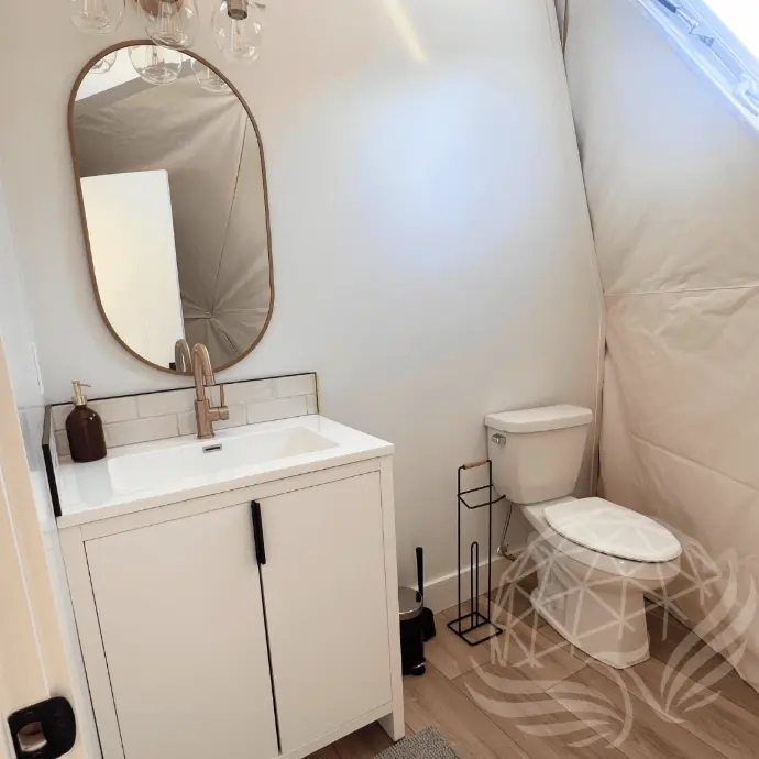 modern toilet with cabinet and mirror inside a geodesic dome
