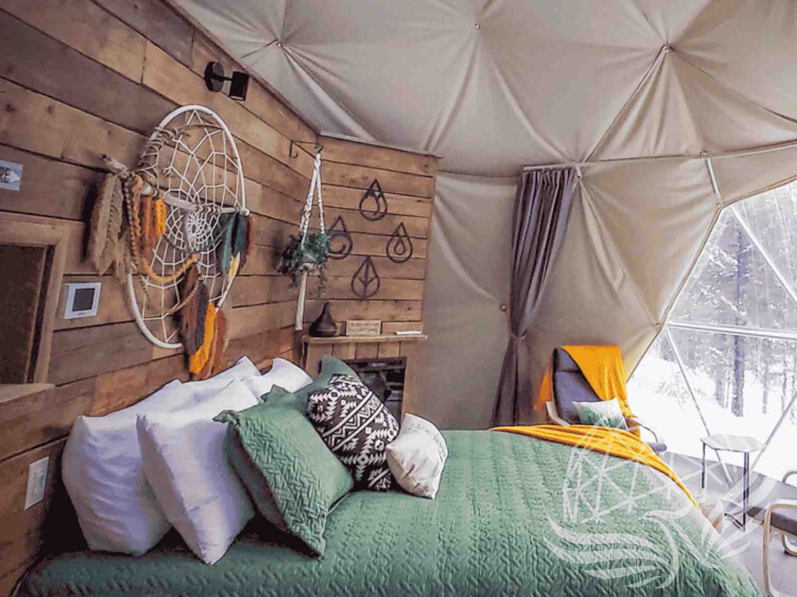 Boho dome bedroom interior with dreamcatcher, wood wall, and cozy green bedding