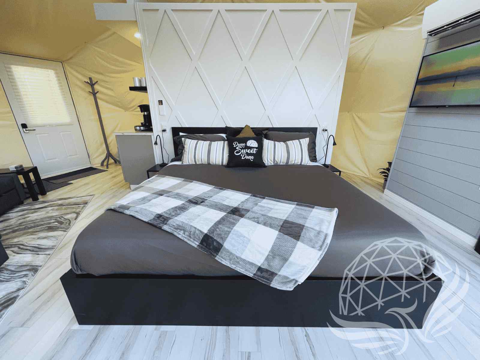 Modern dome interior with black frame bed, TV, and white panel wall