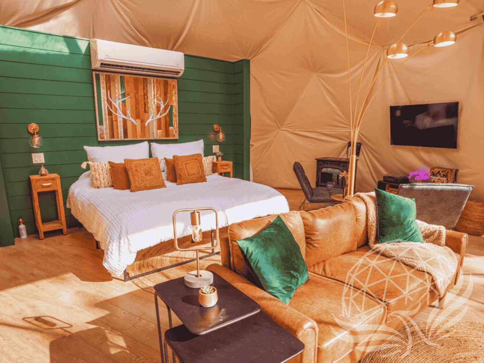 Warm dome suite with leather couch, green pillows, and king bed
