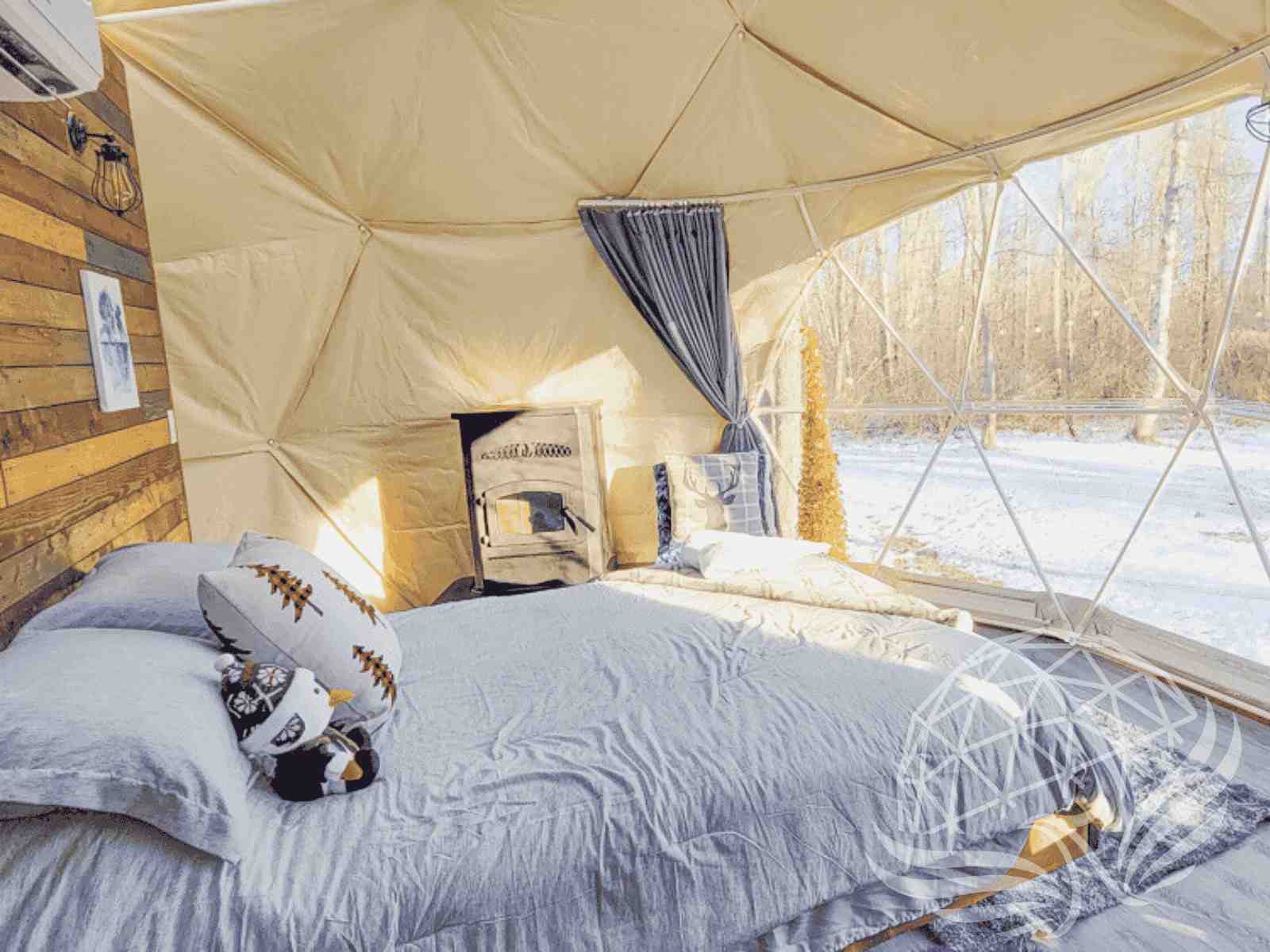 Minimalist dome bedroom with stove and panoramic winter landscape