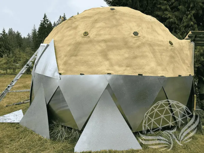 Exterior Spray Foam Insulation for Geodesic Domes Geodesic dome exterior partially covered with spray foam insulation and metal paneling during construction.