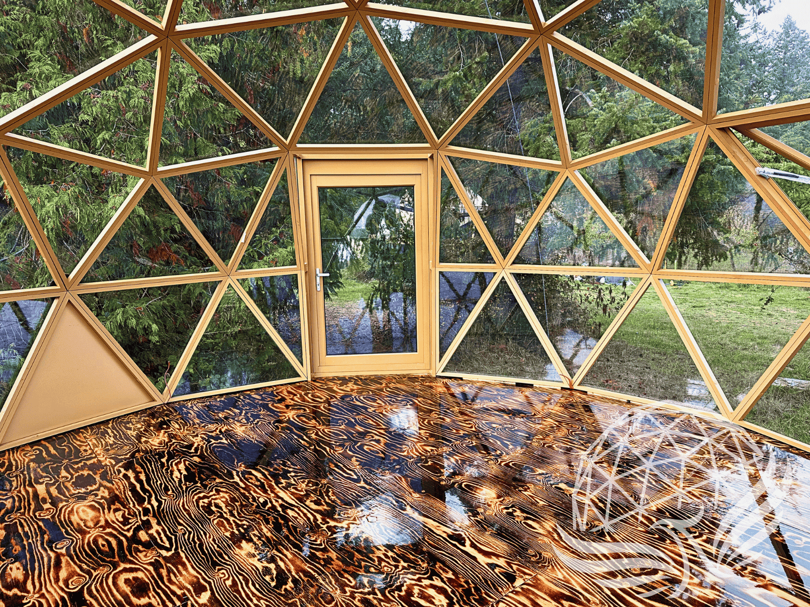 Interior of Phoenix Domes glass geodesic dome with warm wood frame and high-gloss wood floor.