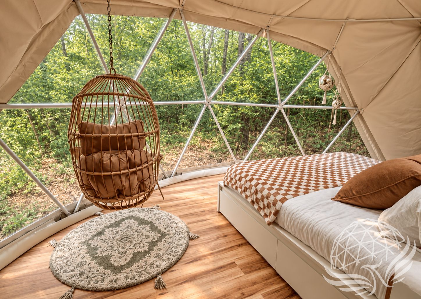 Interior view of a Moonshine Dome Retreat with hanging chair, scenic forest backdrop, and cozy bed